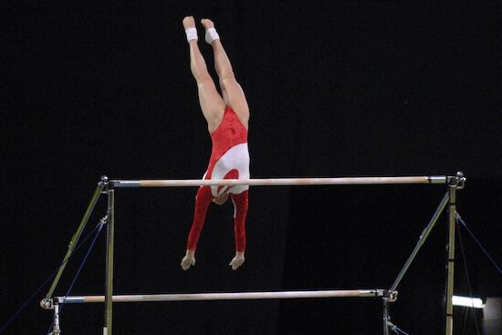 A female gymnast preforms a routine on the uneven bars during competition.